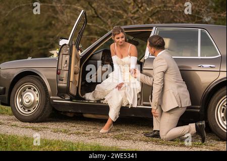 Lustige, ungewöhnliche, stilvolle, originelle Fotos mit Rollenumkehr eines jungen, attraktiven Brautpaares mit wunderschönen Veteranenautos in der Natur. Stockfoto