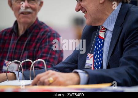 Windham, Usa. Januar 2024. Ein Wahlmitarbeiter, der eine amerikanische Flagge trägt, unterhält sich mit einem Kollegen, während die Leute am 23. Januar 2024 in der New Hampshire Primary an einer Wahlstelle an der Windham High School in Windham, New Hampshire, abstimmen. Der Republikaner Haley hofft, den ehemaligen US-Präsidenten Donald J. Trump bei den Umfragen in New Hampshire zu besiegen, während der Demokrat Dean Phillips hofft, an Dynamik gegen Präsident Joe Biden gewinnen zu können . Foto: Amanda Sabga/UPI Credit: UPI/Alamy Live News Stockfoto