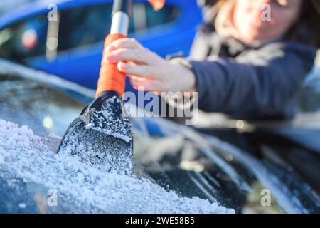 Frau, die Autoscheibe mit Eiskratzer enteist, selektiver Fokus Stockfoto