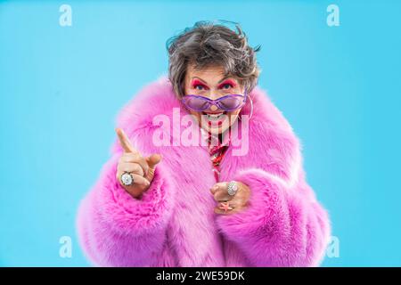 Glückliche und lustige ältere Frau, die anziehende Kleidung auf buntem Hintergrund trägt - modernes cooles Großmutterporträt, Konzepte über ältere und Stockfoto