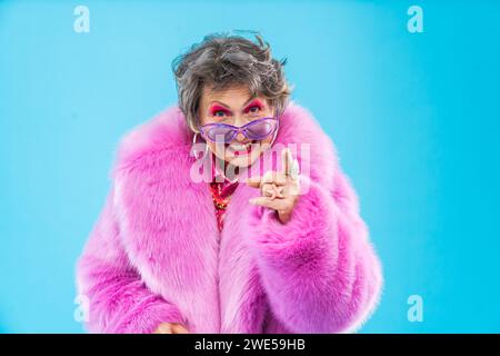 Glückliche und lustige ältere Frau, die anziehende Kleidung auf buntem Hintergrund trägt - modernes cooles Großmutterporträt, Konzepte über ältere und Stockfoto