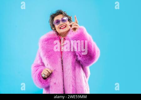 Glückliche und lustige ältere Frau, die anziehende Kleidung auf buntem Hintergrund trägt - modernes cooles Großmutterporträt, Konzepte über ältere und Stockfoto