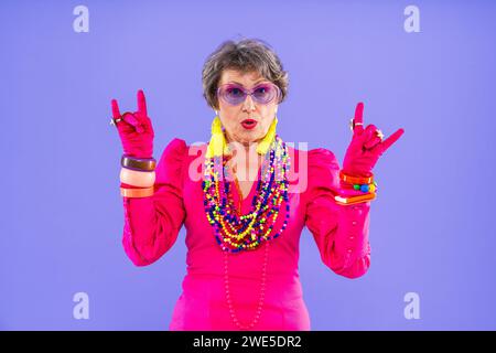 Glückliche und lustige ältere Frau, die anziehende Kleidung auf buntem Hintergrund trägt - modernes cooles Großmutterporträt, Konzepte über ältere und Stockfoto