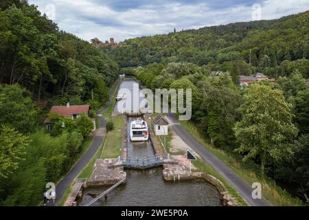 Aus der Vogelperspektive eines Hausbootes Le Boat Horizon 5 in der Schleuse auf dem Canal de la Marne au Rhin mit der Burg Château de Lutzelbourg in der Ferne, Lutz Stockfoto