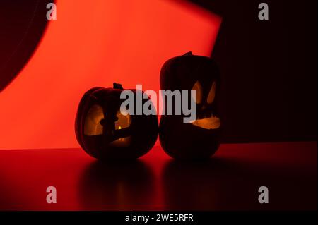 Zwei Jack-o-Laternen leuchten im Dunkeln auf rotem Hintergrund. Halloween Dekoration. Stockfoto