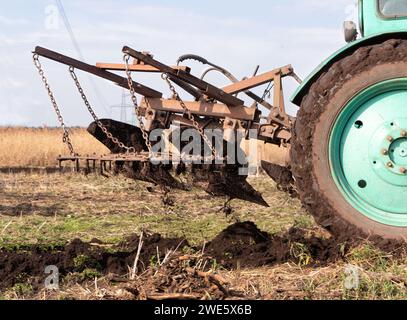 Traktor pflügt das Feld, Nahaufnahme. Landwirtschaftliche Arbeit auf dem Feld im Frühjahr. Seitenansicht. Stockfoto