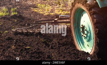 Traktor pflügt das Feld, Nahaufnahme. Landwirtschaftliche Arbeit auf dem Feld im Frühjahr. Stockfoto
