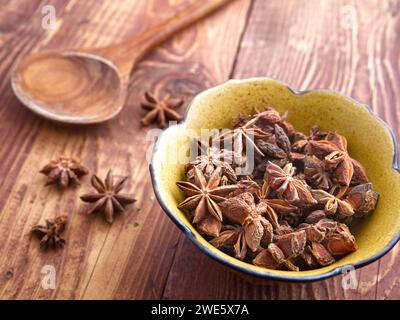 Ein Nahfoto von einem Haufen getrockneten Sternanis in einer Schüssel auf einem Holztisch. Stockfoto