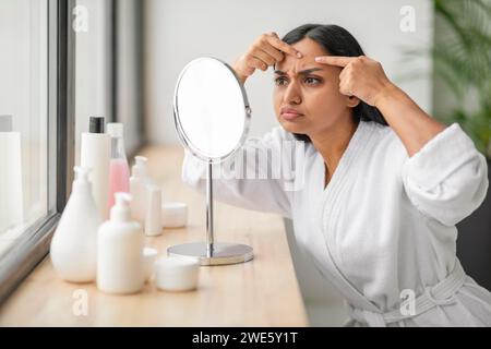 Porträt einer verärgerten, schönen jungen indianerin, die in den Spiegel blickt Stockfoto