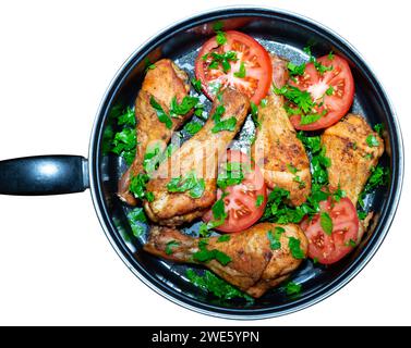 Gebackene Hähnchenschenkel in einer Pfanne. Gekochte Hähnchenschenkel sind mit Tomaten und Gemüse dekoriert. Stockfoto