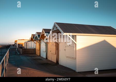 Eine Reihe von hölzernen Strandhütten, die in Pastellfarben hell bemalt sind, am Meer Stockfoto