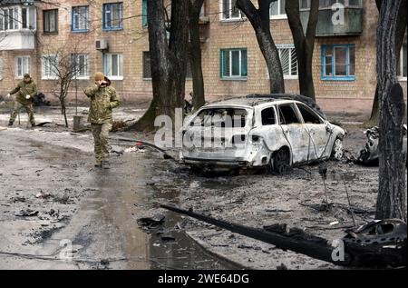 Kiew, Ukraine. Januar 2024. KIEW, UKRAINE - 23. JANUAR 2024 - zwei Soldaten werden von einem Auto gesehen, das infolge des Sturzes russischer Raketenabfälle vor einem Wohngebäude im Bezirk Sviatoschynskyi Feuer gefangen hat, nachdem der russische Raketenangriff am Dienstag Morgen, den 23. Januar, in Kiew, Hauptstadt der Ukraine, stattgefunden hatte. Quelle: Ukrinform/Alamy Live News Stockfoto