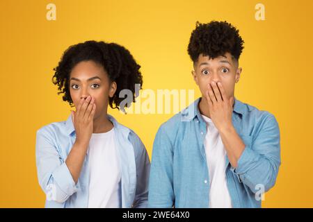 Eine junge Frau und ein junger Mann in lässiger Kleidung stehen Seite an Seite, beide sehen überrascht aus Stockfoto