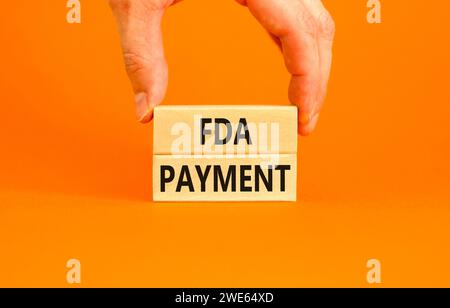 Zahlungssymbol FDA Food and Drug Administration. Konzeptworte FDA-Zahlung auf schönen Holzblöcken. Wunderschöner orangener Tischhintergrund. Geschäftsmann Stockfoto