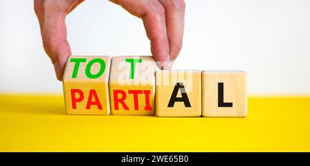 Symbol „Gesamt“ oder „Teil“. Geschäftsmann verwandelt wunderschöne Holzwürfel und ändert das Wort Partial in Total. Schöner gelber Tisch mit weißem Hintergrund. Busi Stockfoto