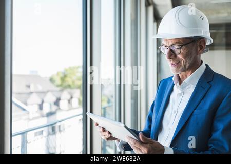 Lächelnder Ingenieur mit Tablet-PC in der Nähe des Fensters Stockfoto