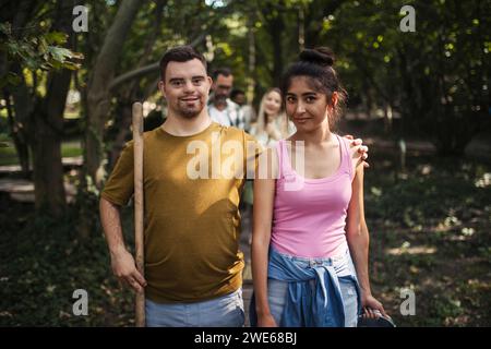 Junger Mann mit Down-Syndrom, der mit seiner Freundin an der Gemeindeaufräumung teilnimmt Stockfoto