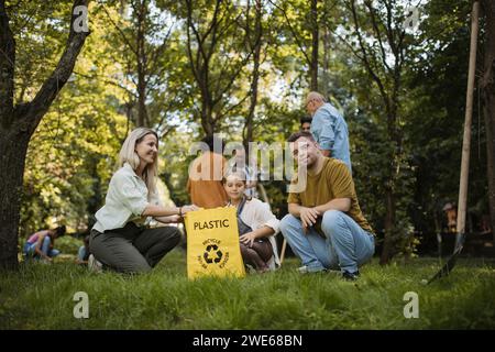 Sozial inkludierende Gruppe von Freiwilligen, die Kunststoffabfälle in Recyclingbeutel legen Stockfoto