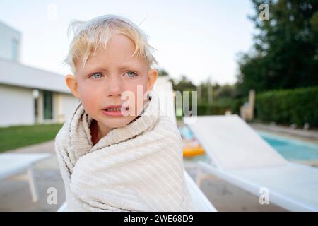 Blonder Junge zittert in Handtuch Stockfoto