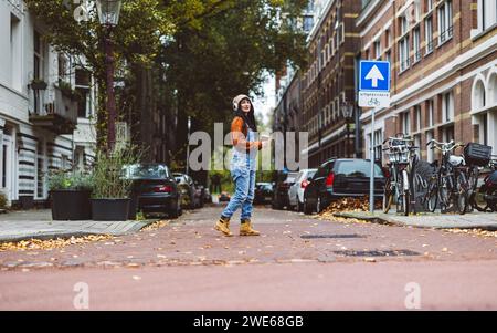 Frau, die auf der Straße in der Nähe von Autos und Fahrrädern vor Gebäuden läuft Stockfoto