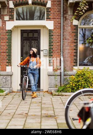 Frau, die mit dem Fahrrad vor dem Gebäude läuft Stockfoto