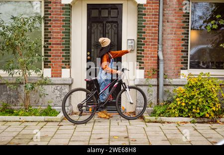 Frau mit Fahrrad, die in das Türsicherheitssystem einrastet Stockfoto