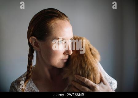 Rothaarige Frau, die Katze zu Hause umschließt Stockfoto