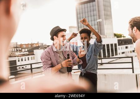 Lächelnde Freunde tanzen und genießen auf dem Dach Stockfoto