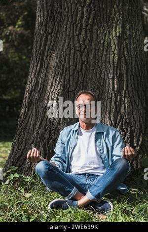 Senior Mann meditiert in Lotusposition im Park Stockfoto