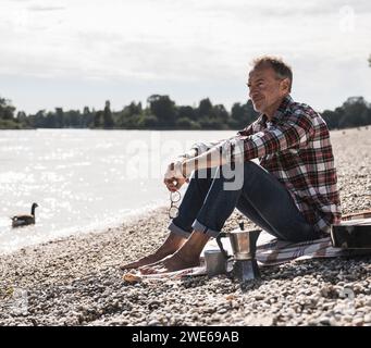 Aufmerksamer Senior Mann, der Freizeit am Meer am Strand verbringt Stockfoto