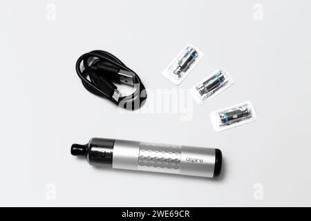 Ukraine, Odesa - 4. Januar 2024: Dampfgerät, Vape Aspire Flexus Stik Pod Kit silberfarben mit Ladekabel USB Typ-C und Netzspulen auf weißem Hintergrund, Ansicht von oben. Stockfoto