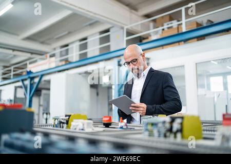 Ingenieur, der Tablet-PCs in der Nähe von Maschinen im Werk verwendet Stockfoto