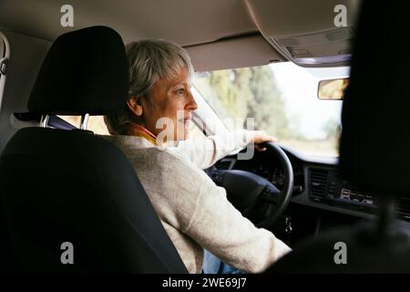 Lächelnde Frau, die auf dem Fahrersitz sitzt Stockfoto