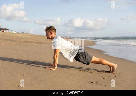 Junger Mann trainiert am Strand auf Sand Stockfoto