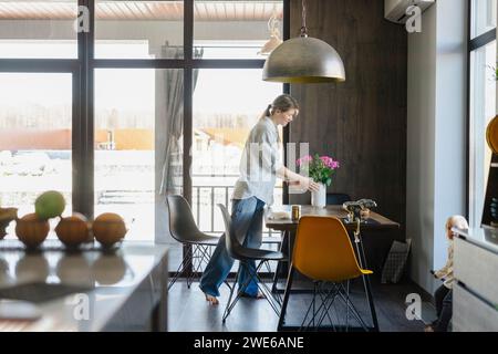 Frau arrangierte Blumenvase und stellte zu Hause einen Esstisch auf Stockfoto