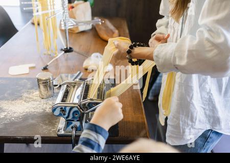 Frau, die Tagliatelle mit Teig im Teigmacher zubereitete Stockfoto