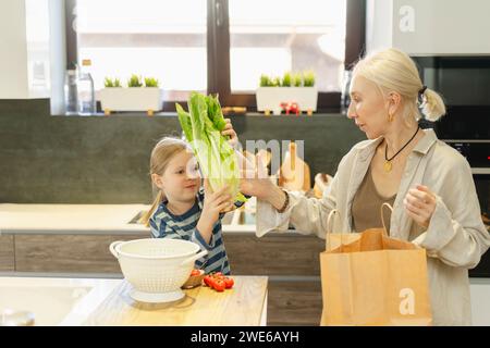 Mädchen, das Großmutter Salat in der Küche zu Hause gibt Stockfoto