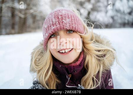 Lächelndes blondes Mädchen mit Strickmütze im Winter Stockfoto