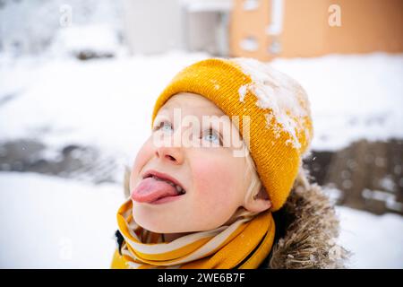 Junge, der im Winter mit der Zunge Schnee fängt Stockfoto