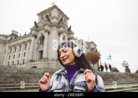 Lächelnde Frau genießt Musik über kabellose Kopfhörer Stockfoto