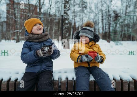 Lächelnde Brüder trinken Tee im Winterpark Stockfoto