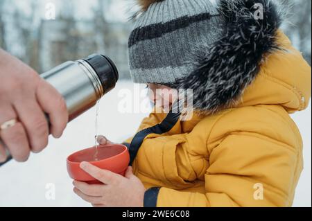 Vater gießt Tee in den Becher des Sohnes Stockfoto