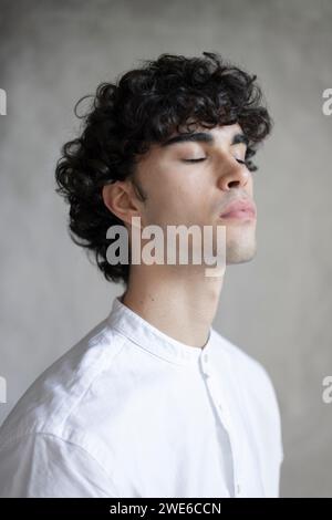 Junger Mann mit lockigen Haaren und weißem Hemd Stockfoto