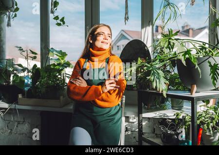 Kontemplativer Botaniker, der sich auf die Fensterbank im Betriebsgeschäft stützt Stockfoto