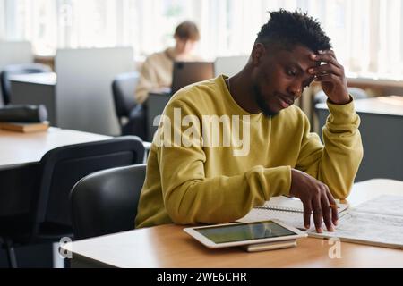 Müde Studentin, die am Schreibtisch in der Bibliothek studiert Stockfoto