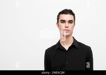 Junger Mann, der ein schwarzes Hemd auf weißem Hintergrund trägt Stockfoto