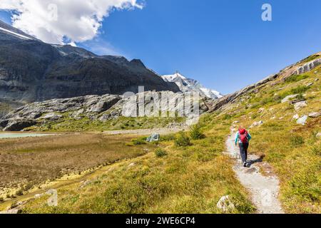 Frau, die auf der Straße in der Nähe der Berge in Großglockner, Österreich, läuft Stockfoto