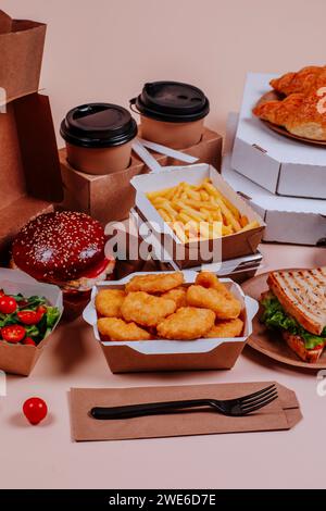 Chicken Nuggets mit Fast Food und Kaffeetassen vor beigefarbenem Hintergrund Stockfoto