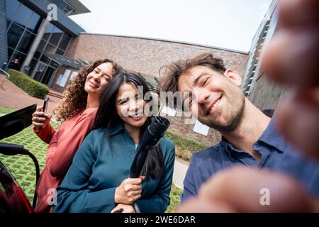 Junger Mann, der Selfie mit Freunden an der Ladestation macht Stockfoto