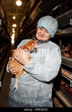 Lächelnder Tierarzt, der Hühner bei Geflügel untersucht Stockfoto